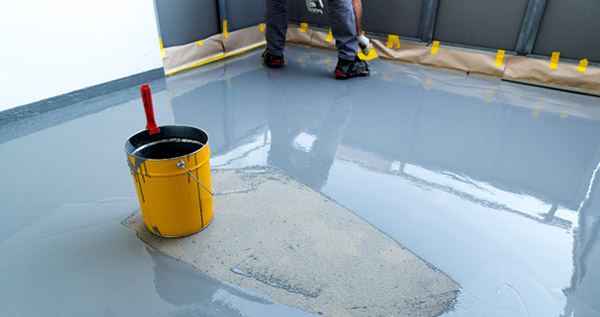 This image shows a man applying epoxy paint on a floor.