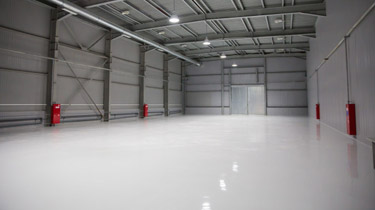 This image shows an empty warehouse with a white epoxy floor.
