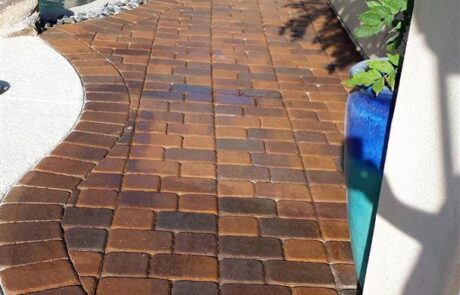 This image shows a pool deck made up of stained pavers.